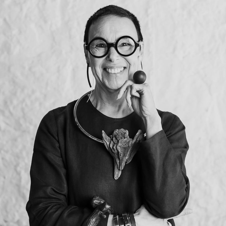A black and white photo of Linda looking into the camera wearing one of her distinctive torque necklaces and large round forest ring