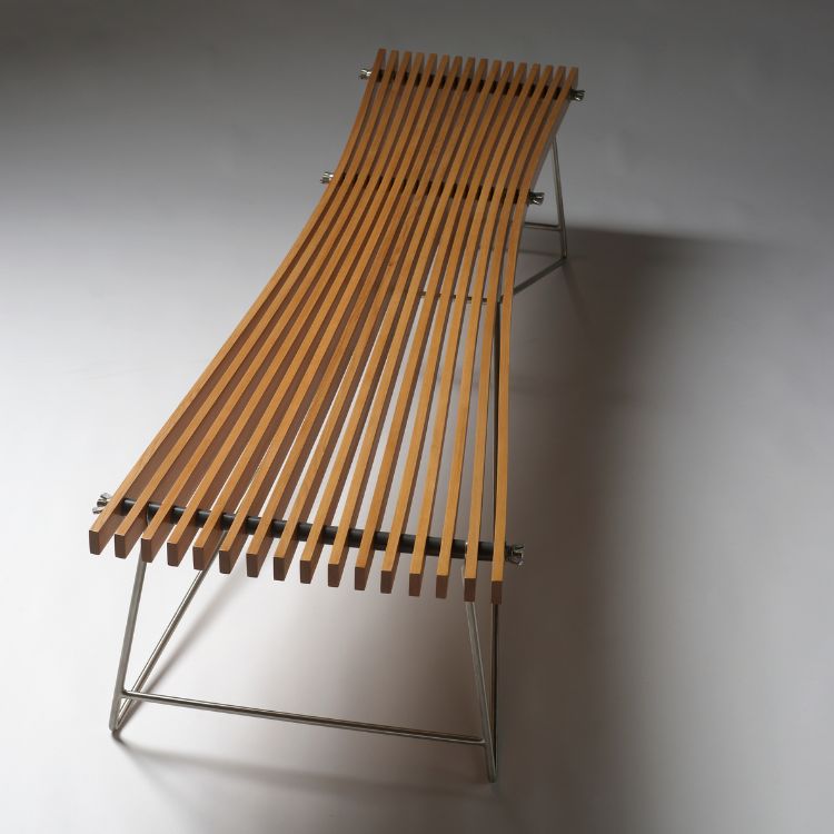 A wooden bench made of strips of wood flaring out at either end. The legs and base are thin metal.