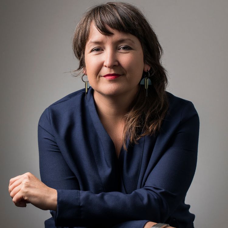 An image of Pippa smiling, looking into the camera wearing a blue top