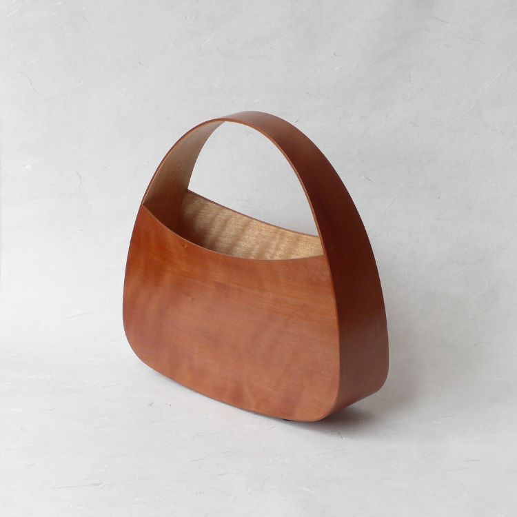 A wooden handbag, curved with wooden handle integrated into the back so it's one solid piece
