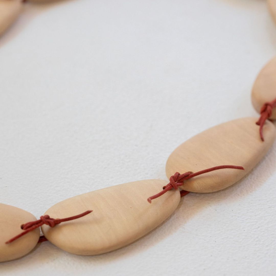 A necklace made of wooden tear drop shapes - except one of the links is stone and the other shapes made from wood in the same shape