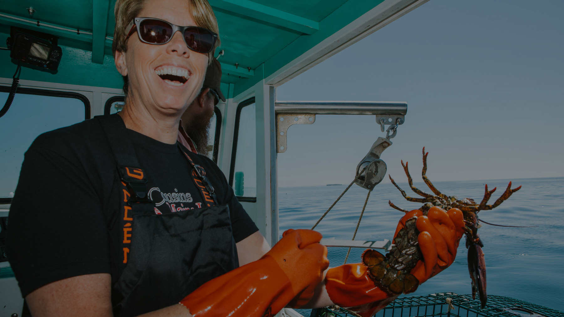 Cousins Maine Lobster Columbus franchise owner holding a lobster on a lobster boat in Maine.
