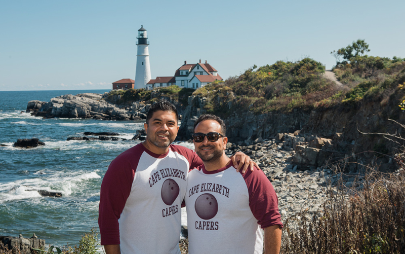 Cousins Maine Lobster franchisees stand with their arms around each other in front of the Portland Head Light in Cape Elizabeth, Maine.
