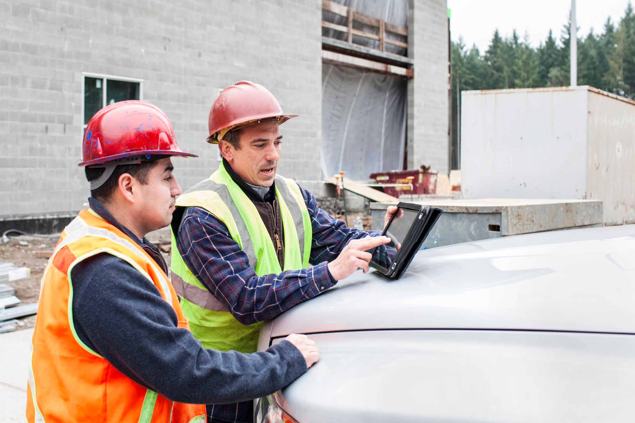 Two workers looking at a tablet out at a project site.