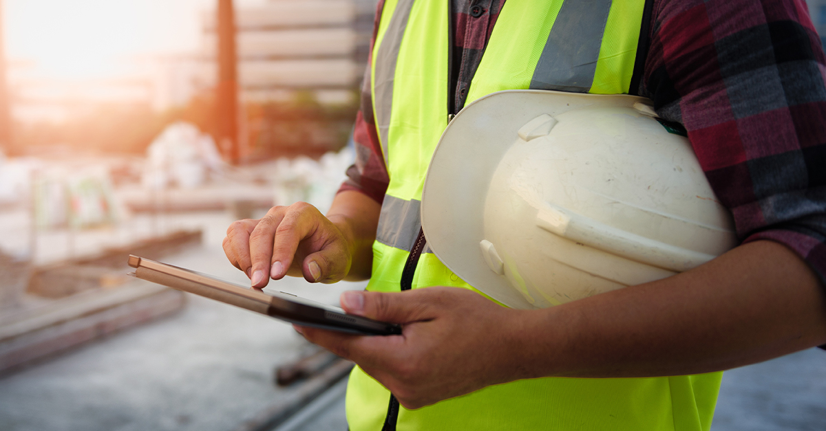 A construction worker accesses jobsite plans on a tablet in the field.