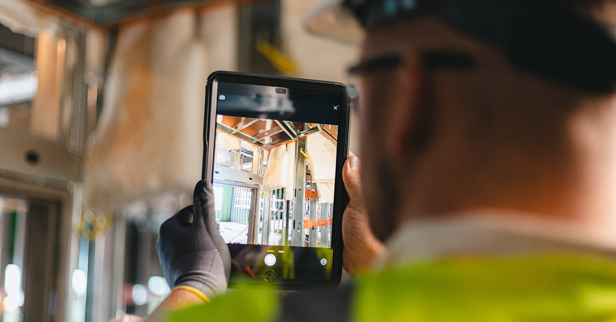 Arbeiter benutzt Tablet auf der Baustelle, um Fotos zu machen