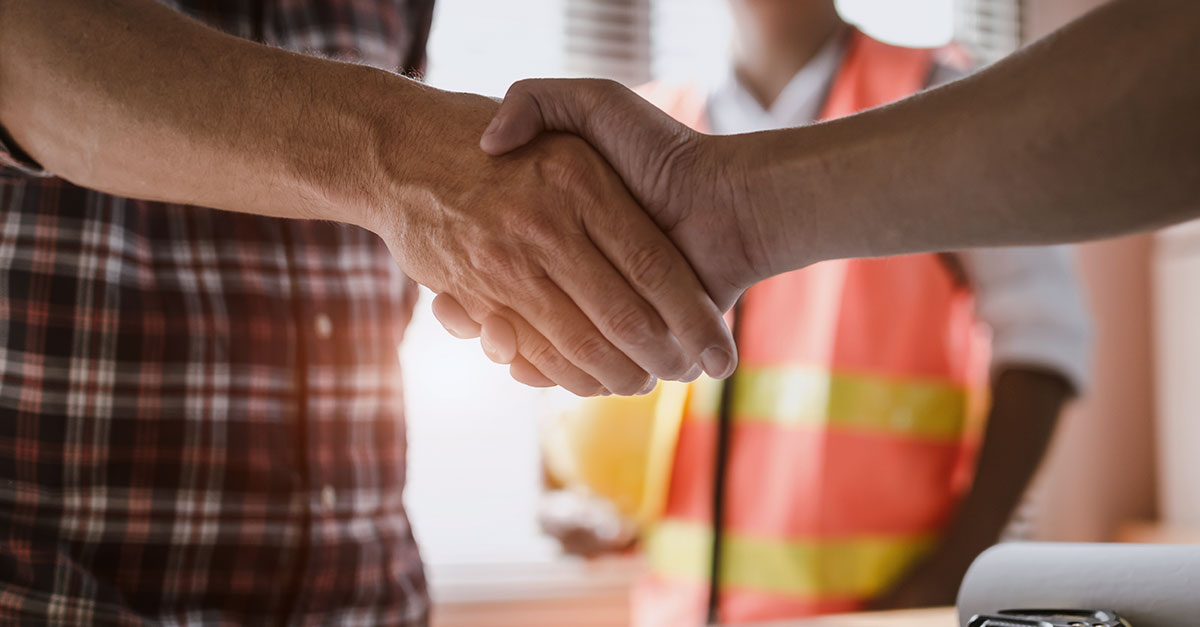 Two people shaking hands in a construction jobsite.