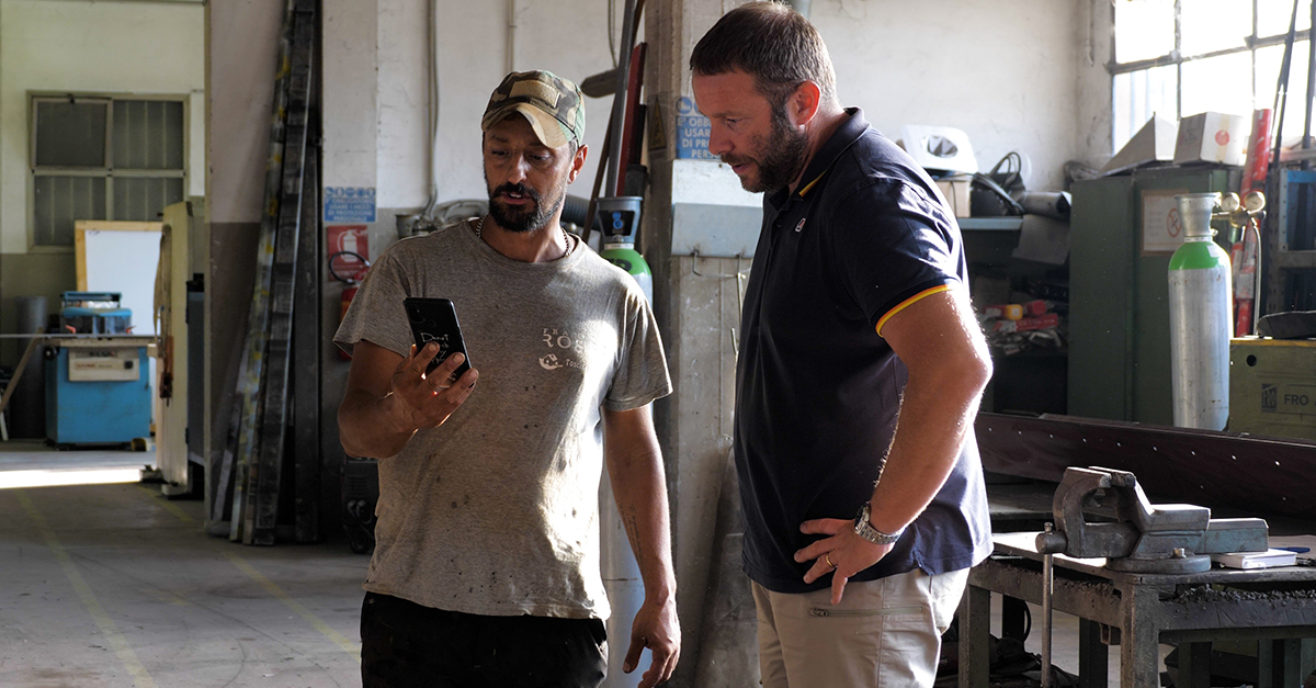 Construction workers from Fratelli Rossi check the project's information on the Fieldwire app using a cellphone.
