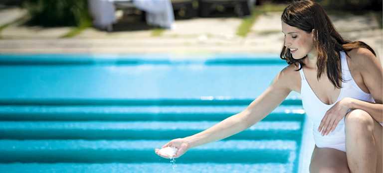 How Easy Is It to Change My Pool to a Mineral Swim Pool?  Woman placing mineral chemicals to her pool.