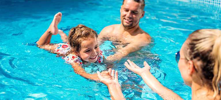 family playing in a pool cleaned by a pool vacuum