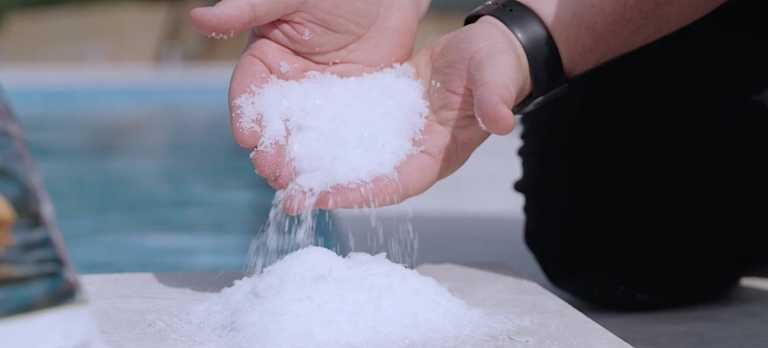 Hand holding mineral pool chemicals.