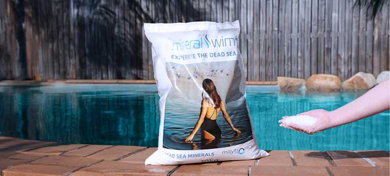 Mineral Swim system use 100- Dead Sea minerals Mineral Swim bag on a pool with a hand that has Mineral Swim chemicals.