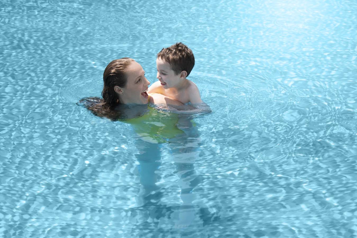 Mother swimming in the pool with her son on her back