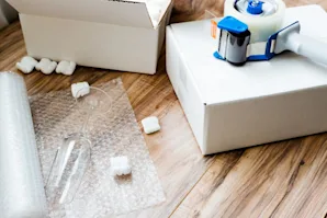 Packing wrap on the floor with boxes and a packing gun.