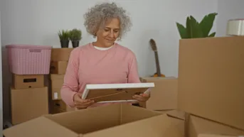 A woman looking at a photo surrounded by boxes