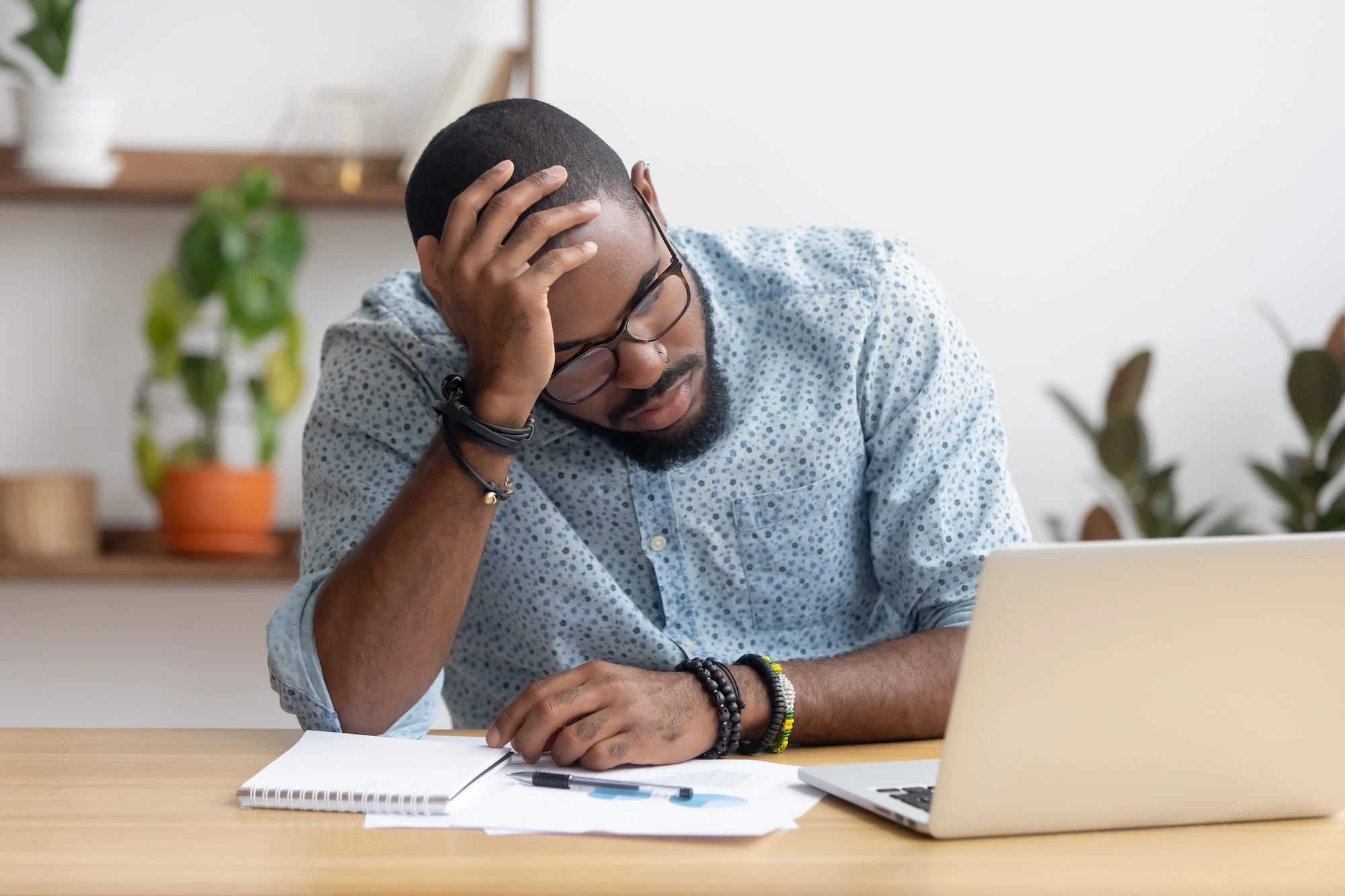 Man at his desk with a blue Poka dot shirt placing his hand on his head