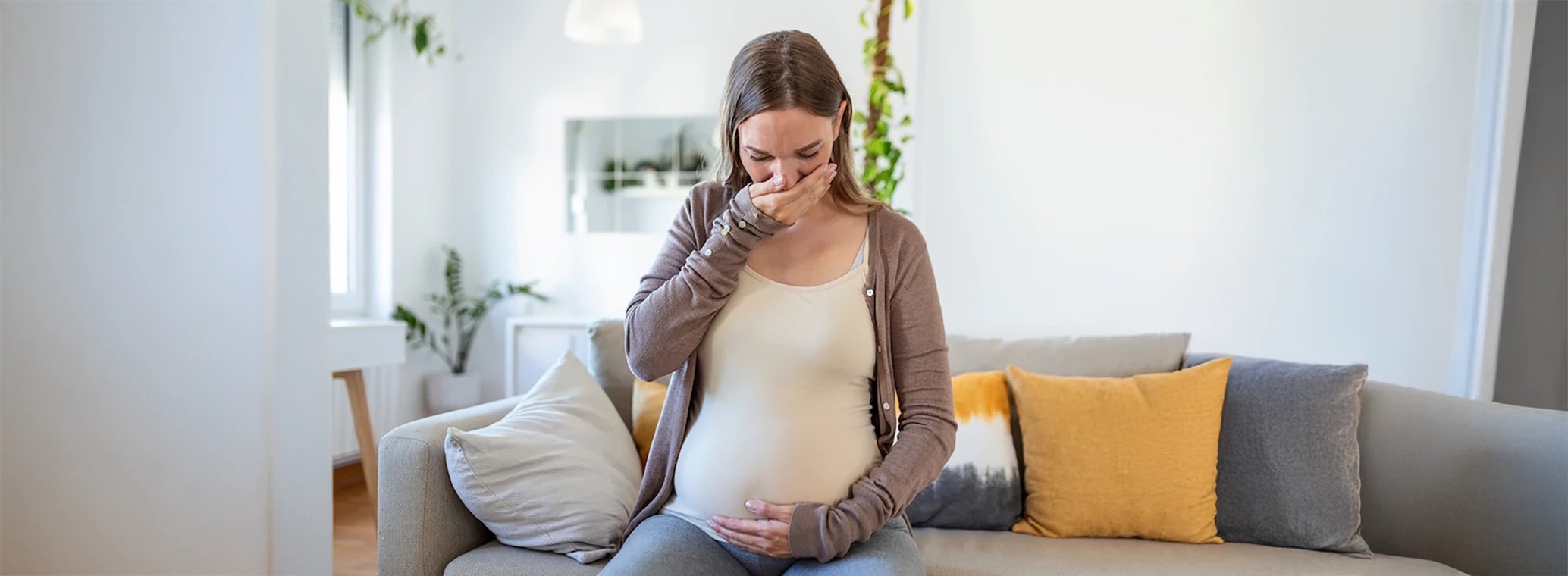 Woman holding her pregnant stomach and experiencing an oral issue