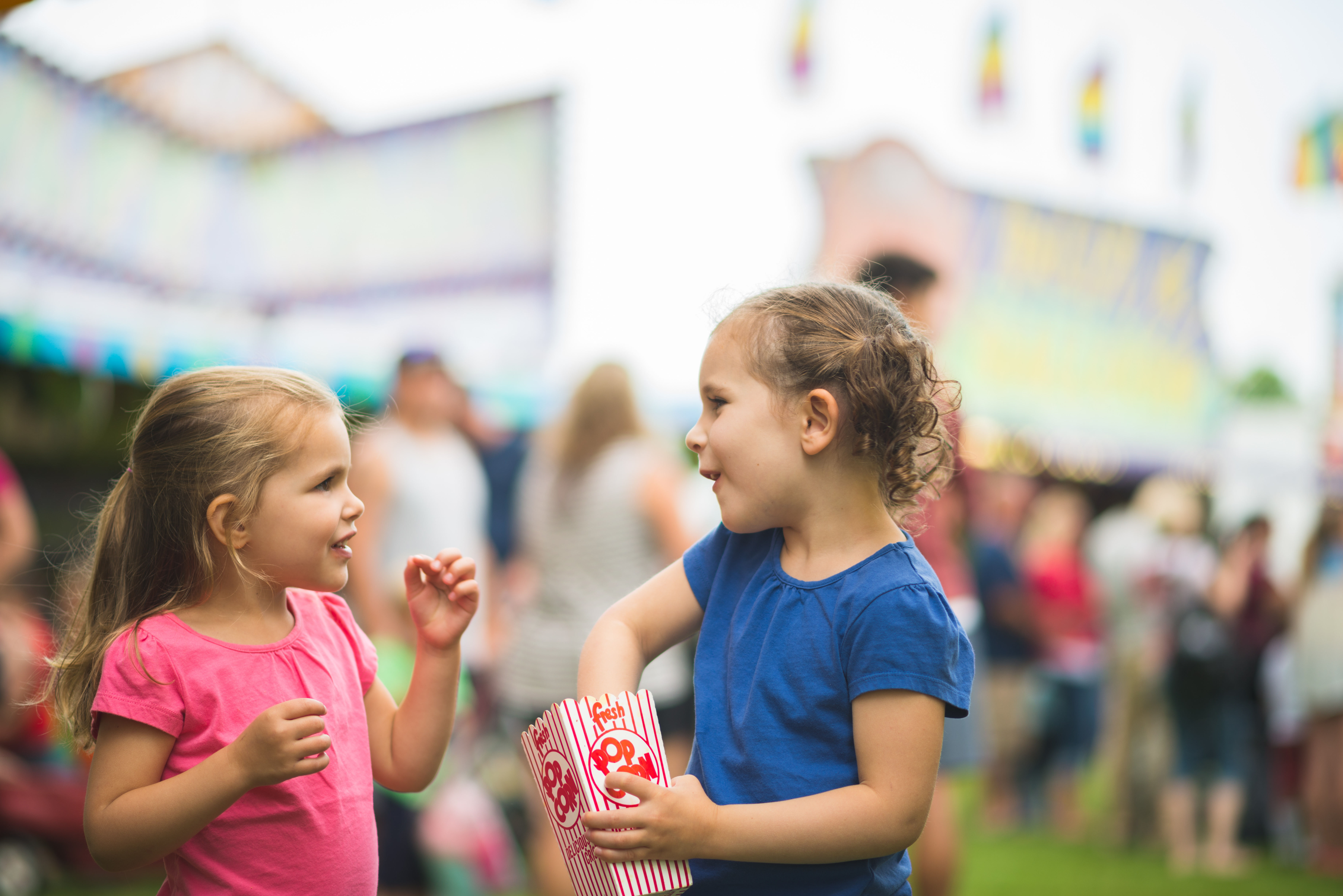 two young girls enjoying popcorn at a fair