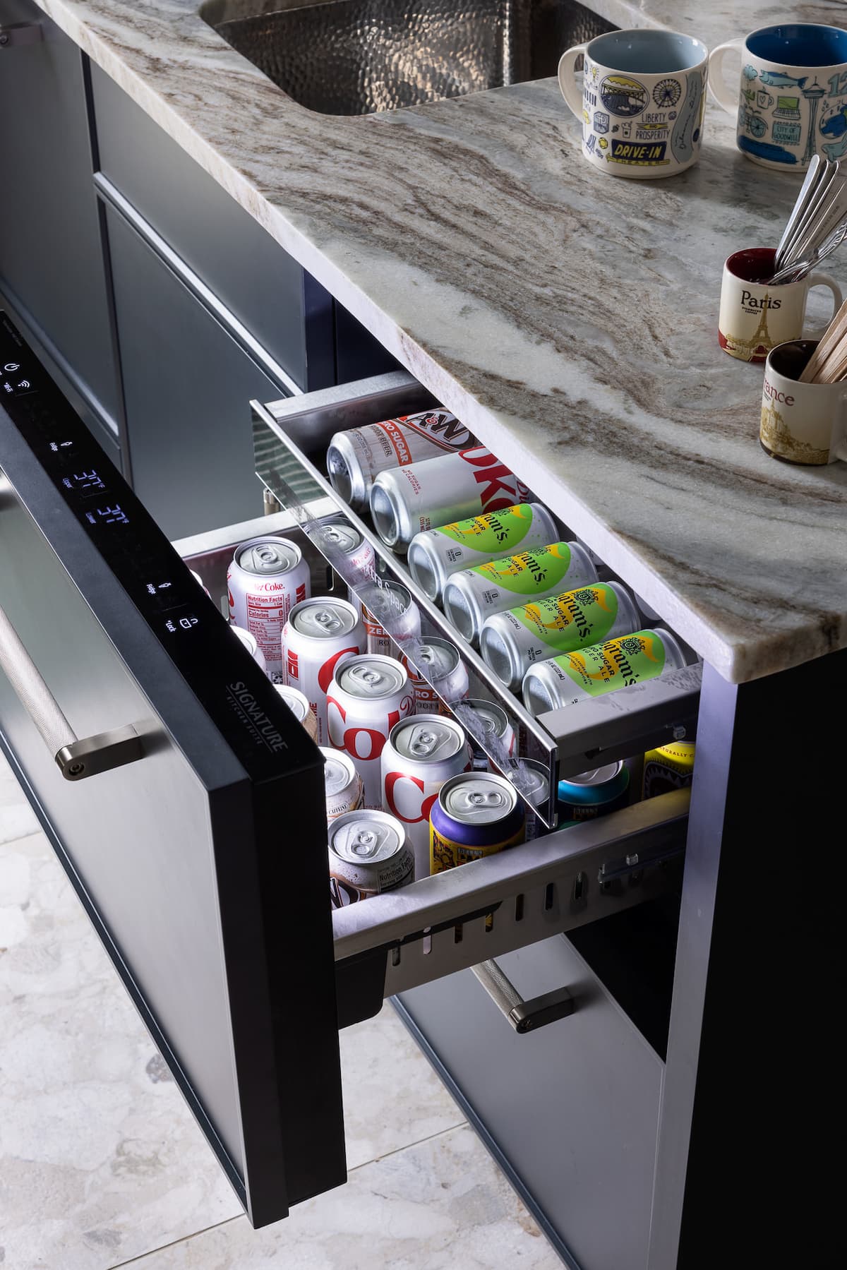 Beverage drawer in a kitchen pulled out, showing two rows of chilled soda cans