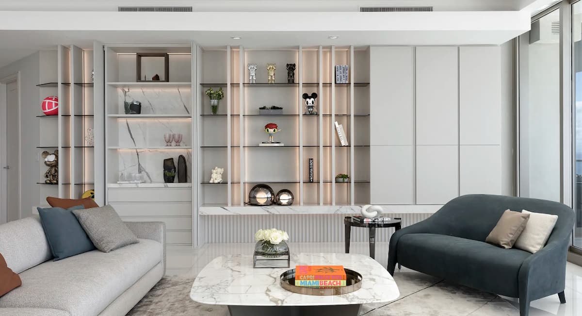 Condo living room with shelving that displays art collection.