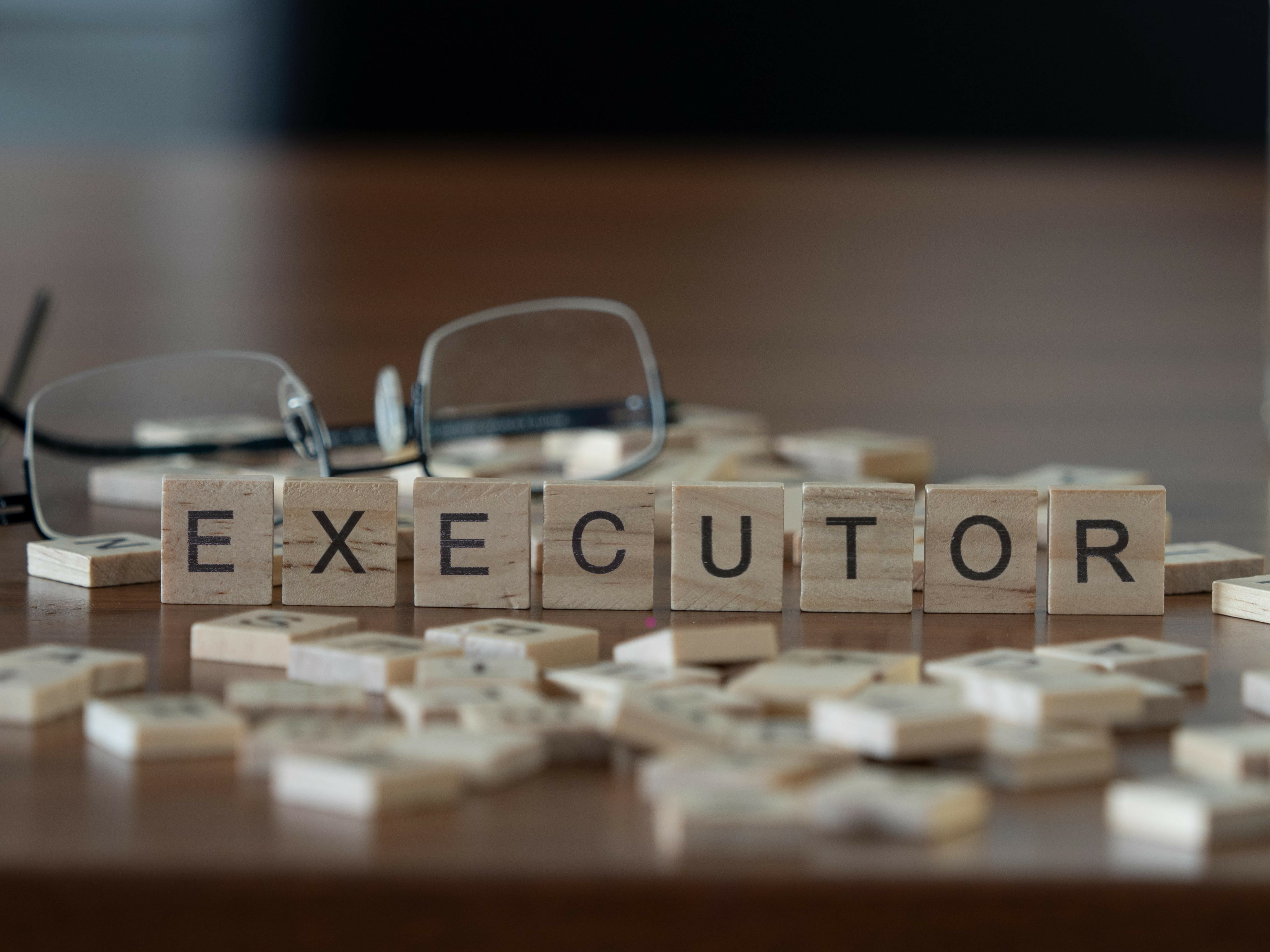 scrabble letters spelling out the word executor with reading glasses to the side