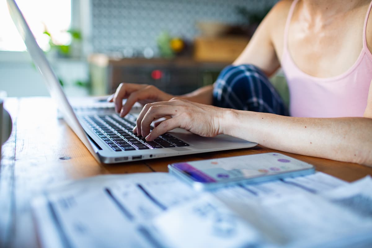 woman with open laptop, calculator, and paperwork