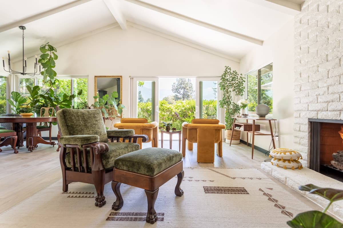 White, bright and airy living room, with lots of plants, large windows and white brick fireplace