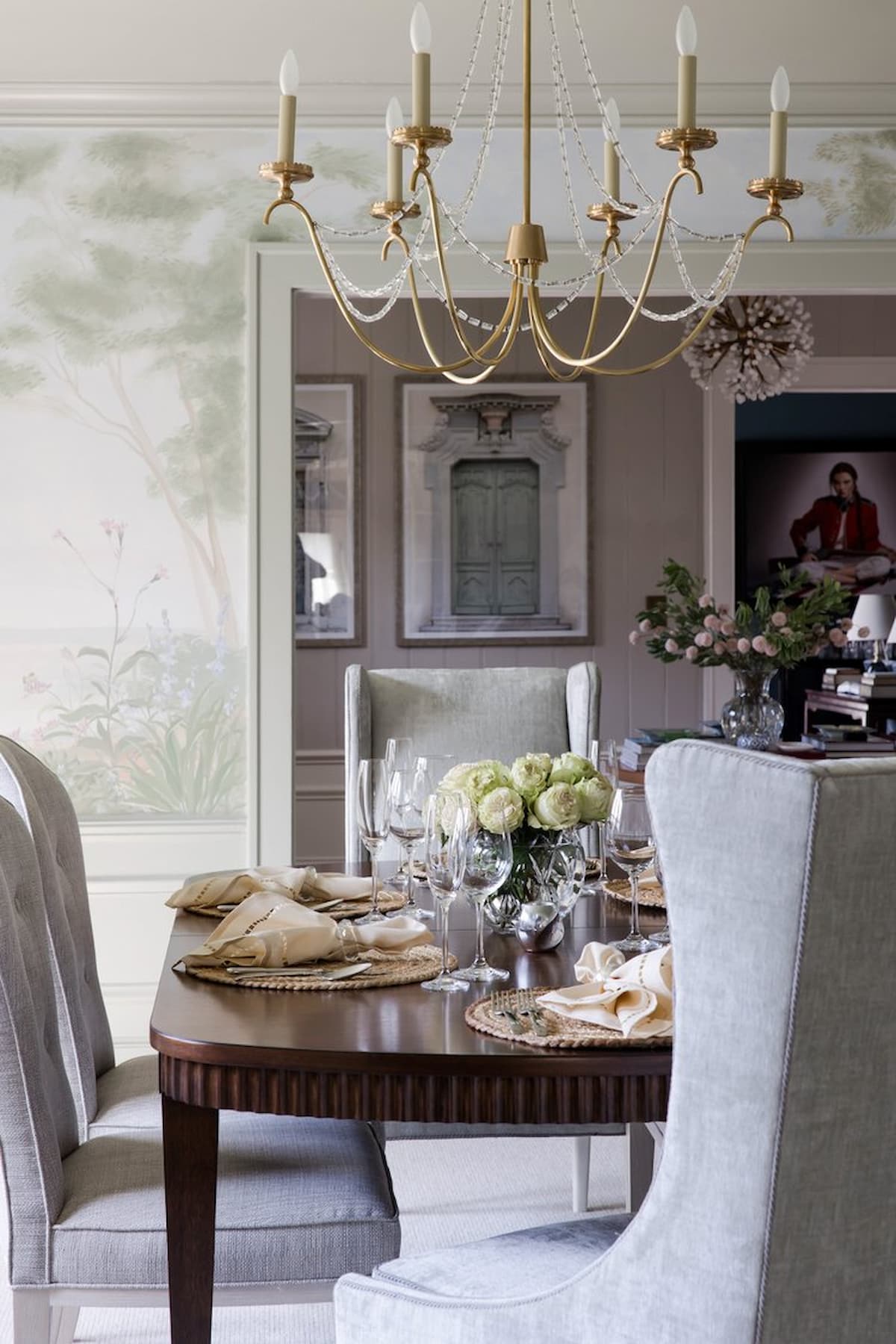 Elegant dining room with chandelier, print green wallpaper and living room in the background