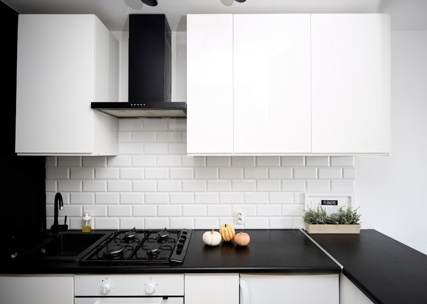 Kitchen with black counters white cabinets and black range hood