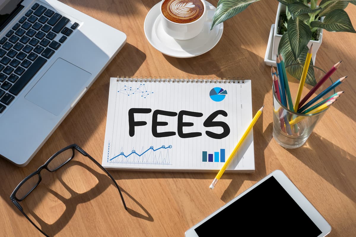 fees sign next to a computer, coffee cup, and pencils