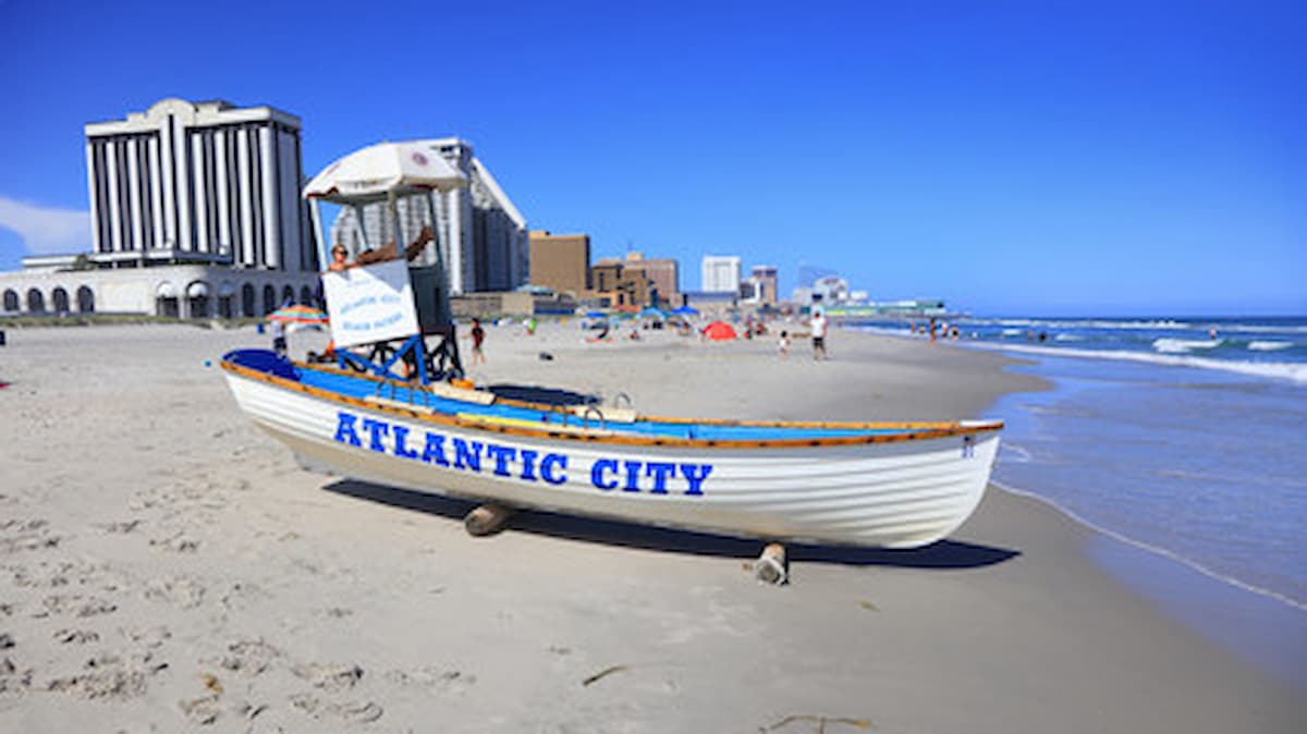 white sailboat next to a lifeguard stand on an Atlantic Ocean beach