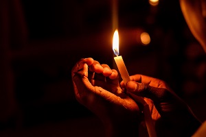 Is UK fuel poverty set to treble? Hand holding candle to keep warm. Person is in fuel poverty as they're unable to afford their energy bills.