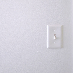 How many people switch energy? White plastic light switch on white wall.