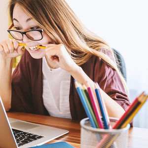 Why are energy suppliers going bust? Image of woman at laptop biting pencil in frustration.