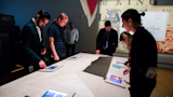 Visitors gather around a table to play the Making Meaning Magna Carta quiz.