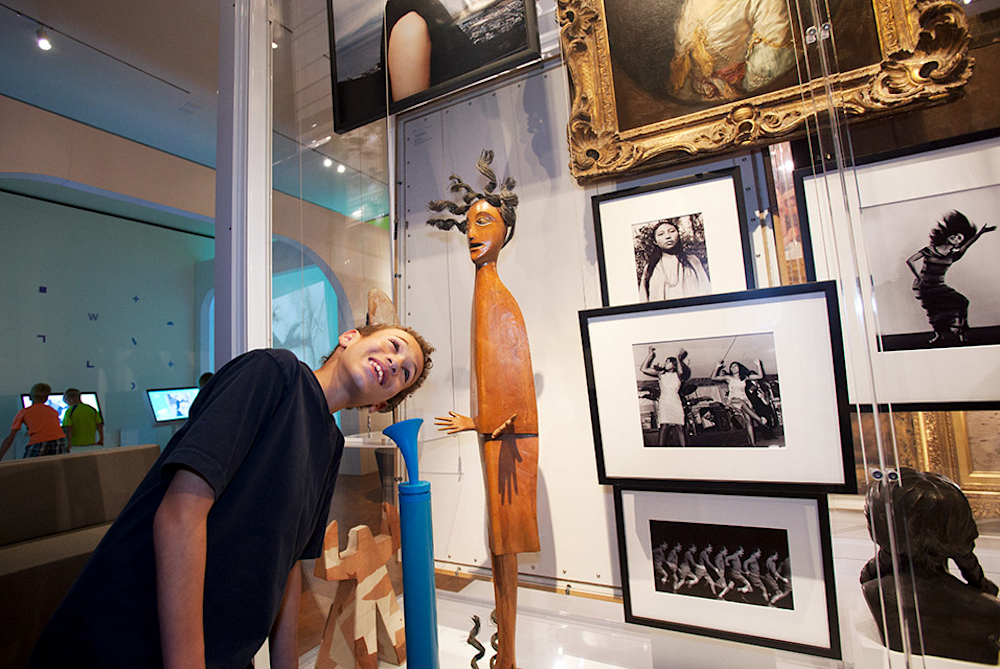 A young visitor listens to artwork-related audio clips on an ear horn attached to the Artquarium artwork case, housing over 50 artworks in the Wonder Studio.