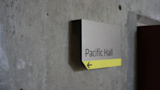 Aluminum sign for Pacific Hall at the University of Oregon AAA school mounted on a concrete wall
