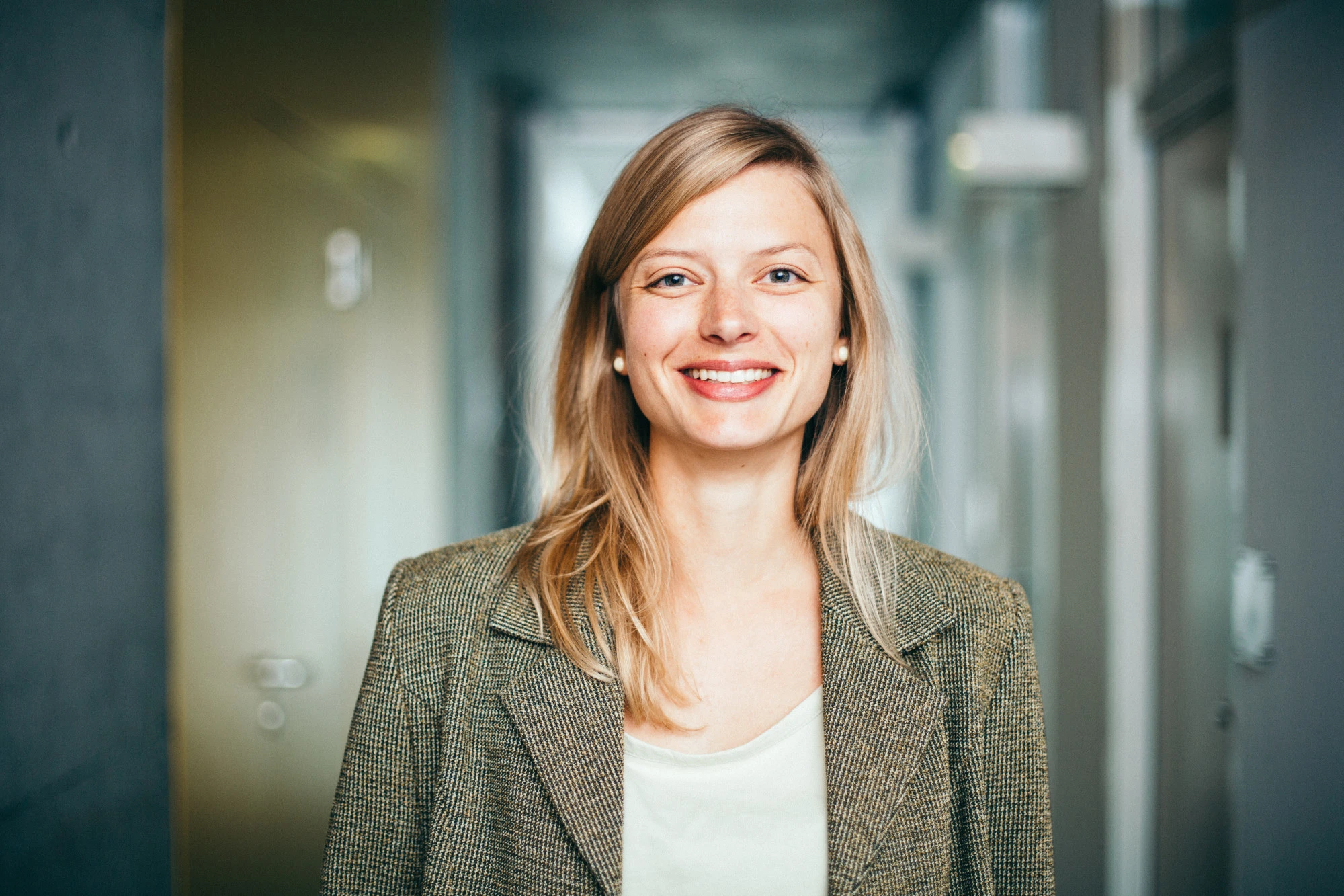 Female professional standing in a hallway smiling