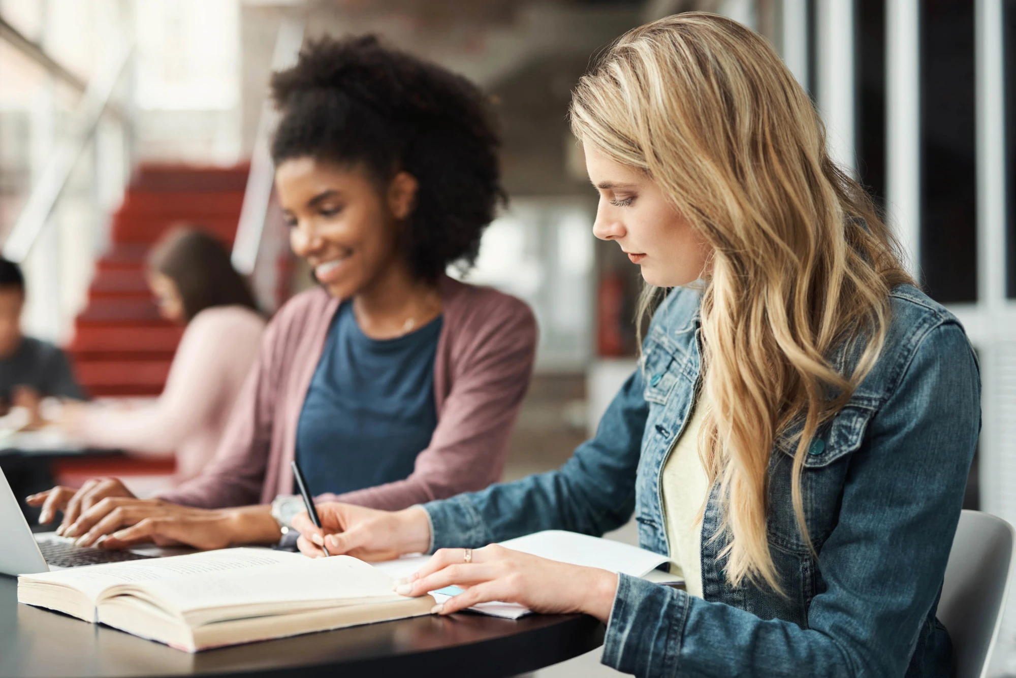 2 women studying with books and laptop at university