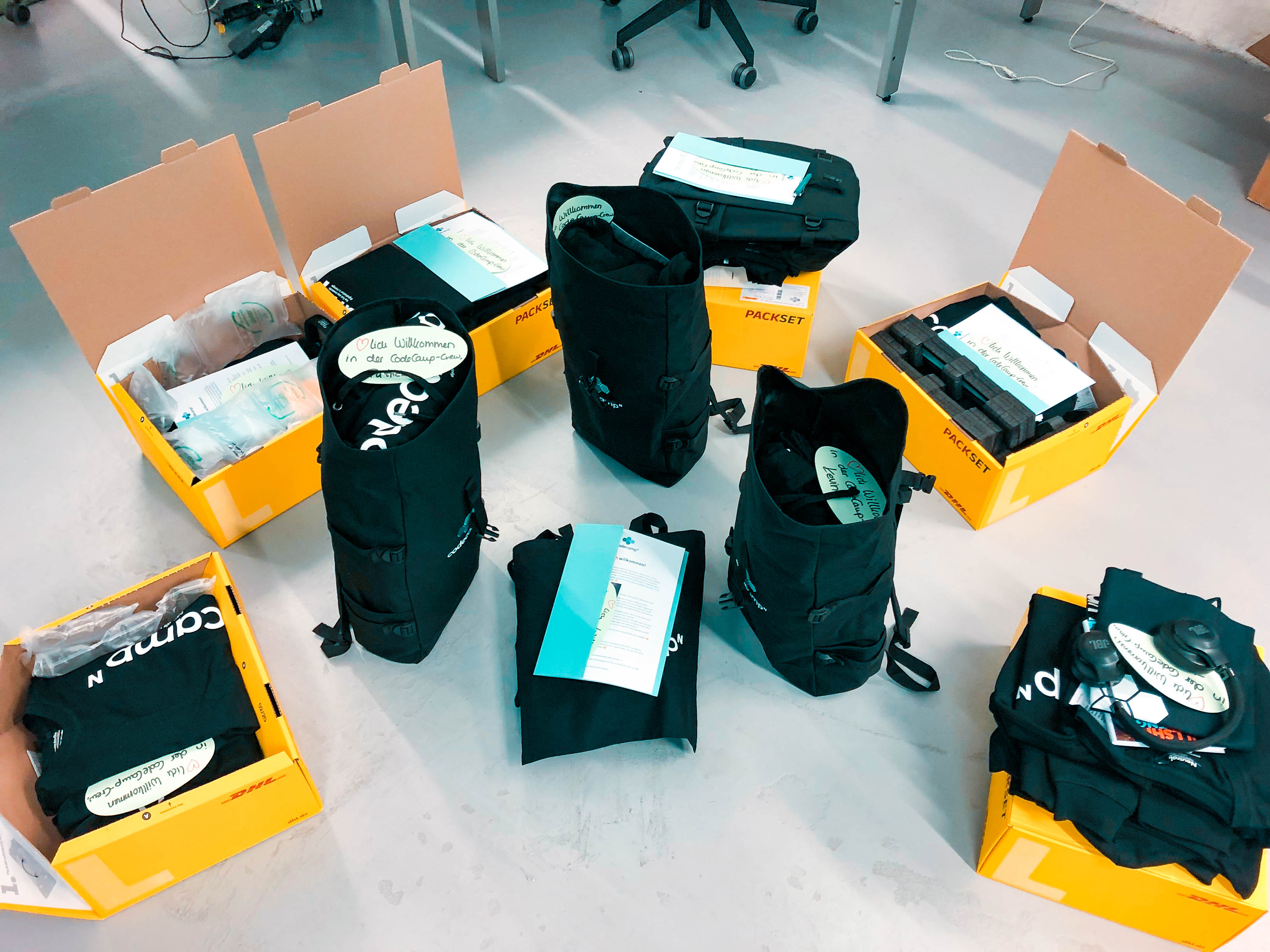 gepackte Pakete auf dem Boden mit Laptop, Unterlagen und Klamotten.