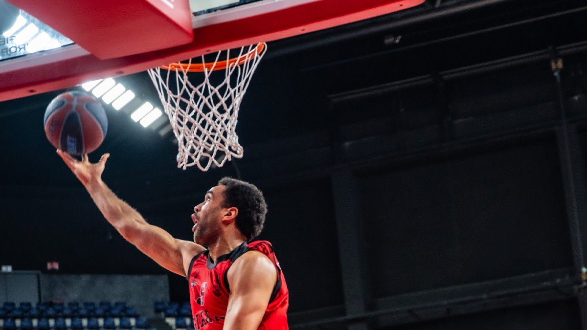 Een speler van Windrose Giants Antwerp in hun rode uniform scoort een punt voor zijn team.