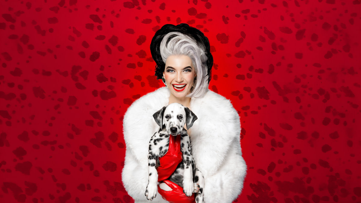 Tinne Oltmans in de typische Cruella de Vil outfit met in haar hand één van de 101 Dalmatiërs.