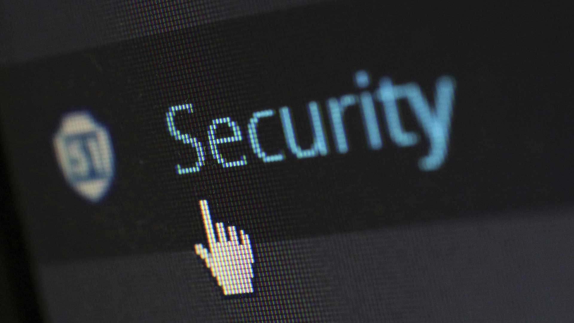 A hand-shaped cursor points to the word “Security” on a computer screen, with a blurred shield icon on the left. The image shows a close-up of an interface indicating security settings.