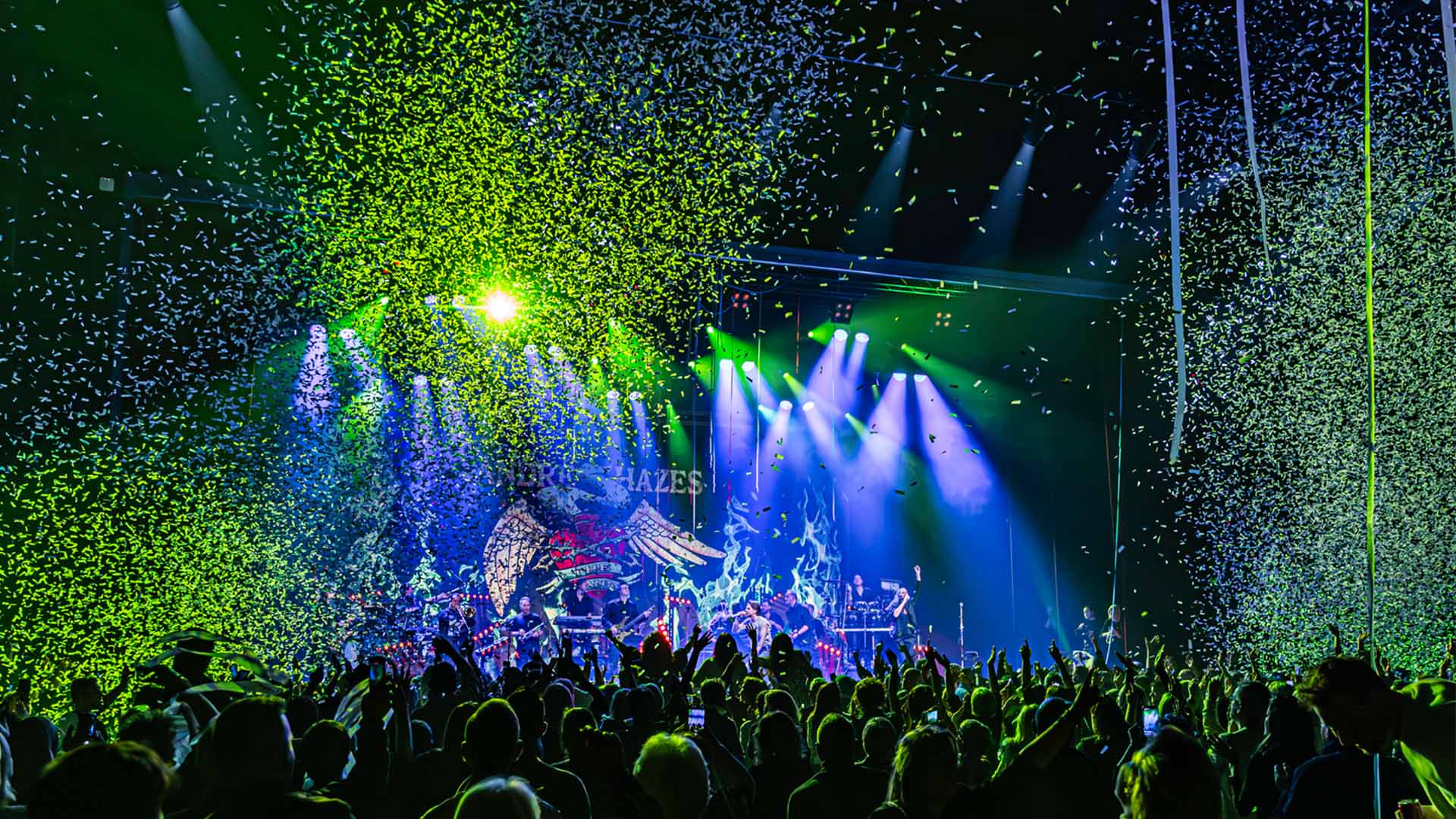 André Hazes en zijn band treden op in Trixxo Theater Hasselt. Het publiek gooit de handen in de lucht en er valt confetti naar beneden.