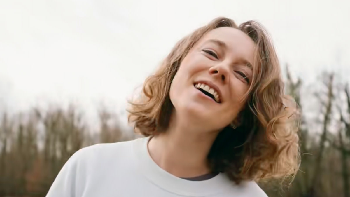 Alexandra Gadzina met halflang blond haar in de openlucht met in de verte een aantal bomen.