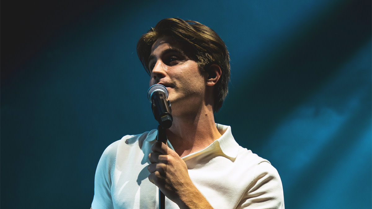 MAKSIM in een wit hemd tegen een blauwe achtergrond tijdens zijn concert in de Lotto Arena.