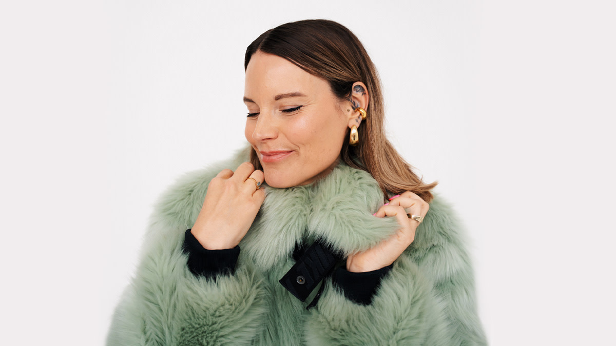 Jolien Roets in een groene warme jas presenteert De schuur Schuur op 'I Love The 90's' in Trixxo Arena.