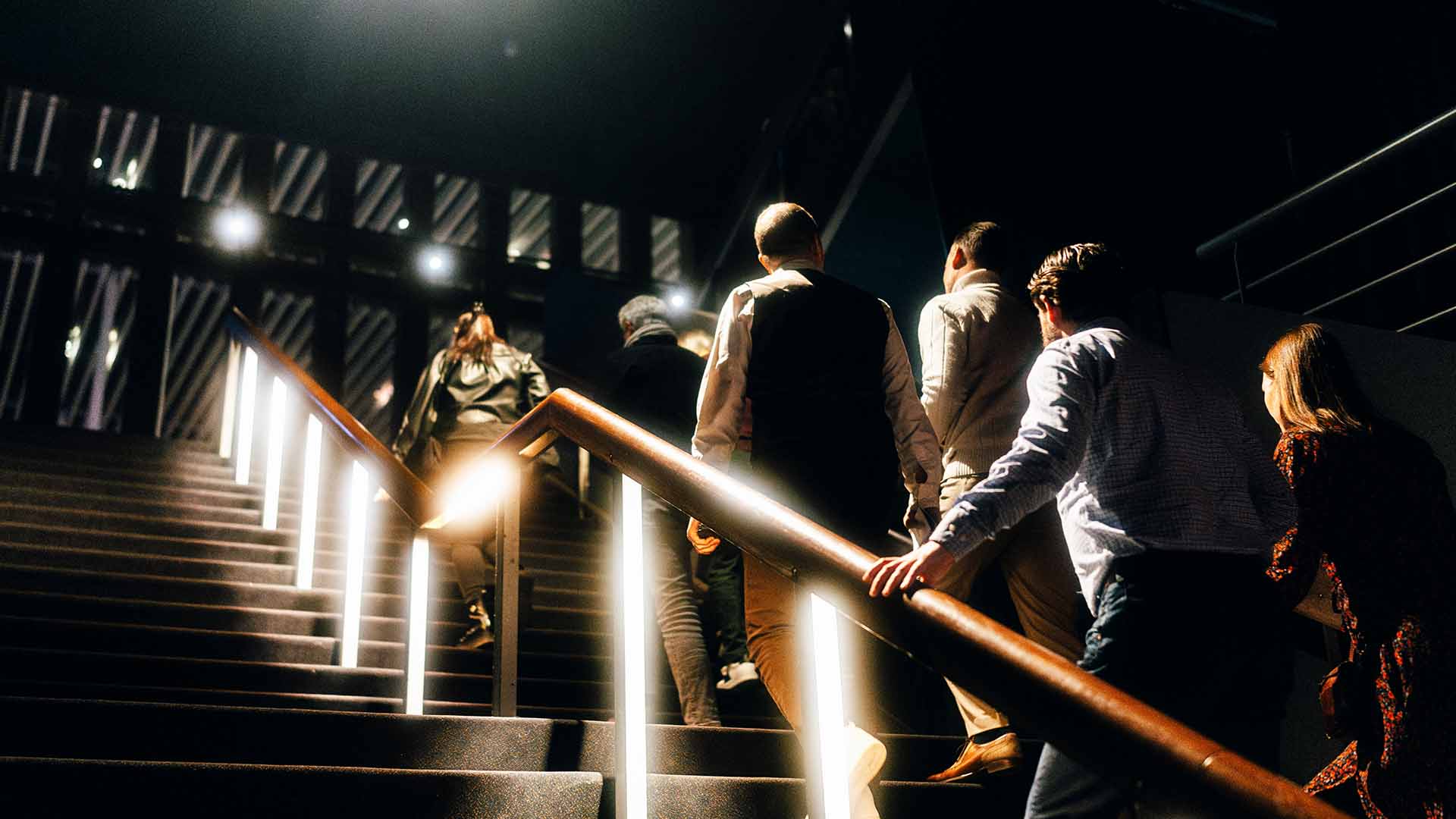 Een groepje mensen loopt de trap op naar de zaal.