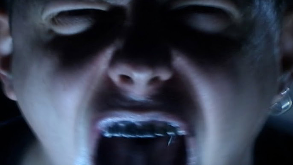 Gros plan sur un visage éclairé d’une lumière bleue, extrait du clip de « Pain » de Chalk.