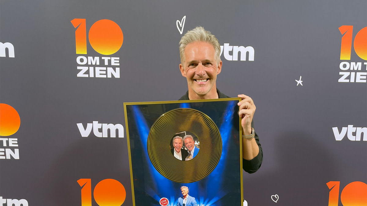 Christoff toont met een brede glimlach de gouden plaat die hij ontving naar aanleiding van het live-album 'Christoff Zingt Tura'.